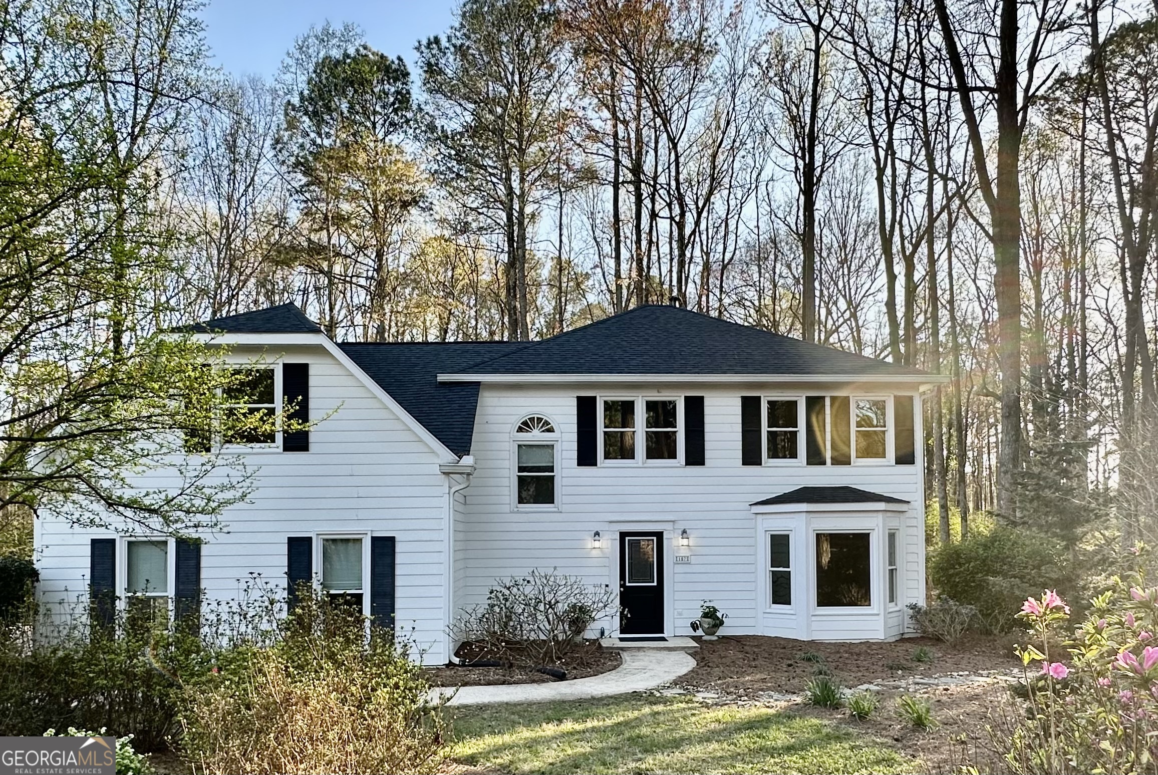 a front view of a house with yard and trees in the background