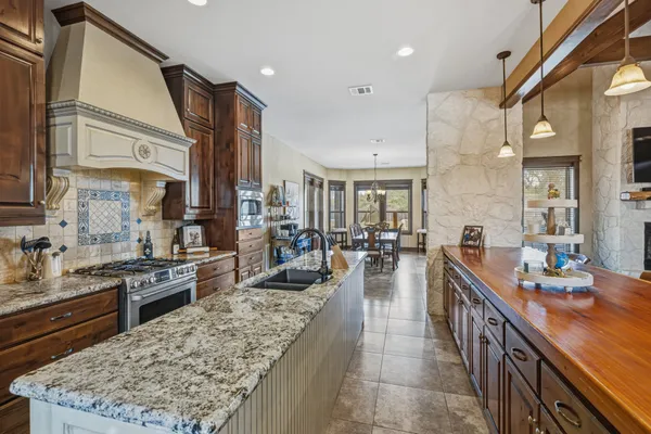 a large kitchen with counter top space a sink stainless steel appliances and cabinets