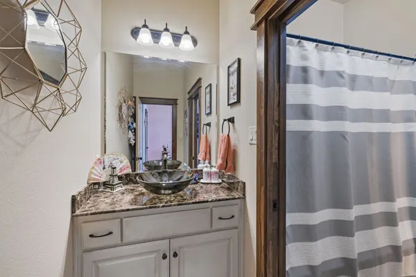 a bathroom with a granite countertop sink a mirror and shower