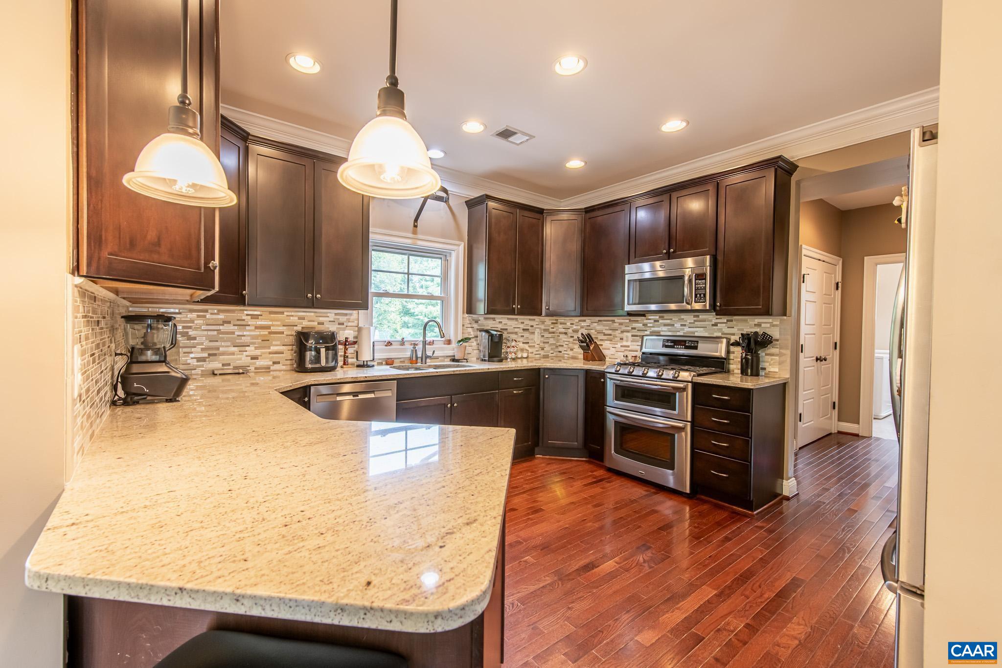 38 Timber Ridge Court Zion Crossroads, VA 22942 - Photo 24 of 72 a large kitchen with stainless steel appliances kitchen island granite countertop a stove a sink a refrigerator and a microwave