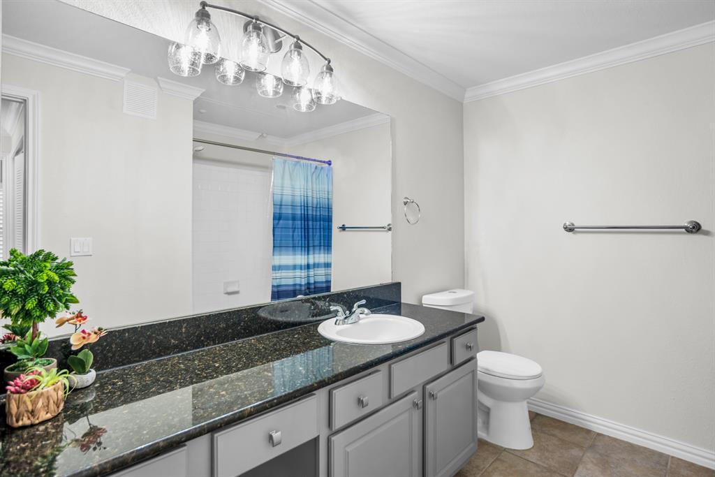 2524 Preston Road, Unit 808 Plano, TX 75093 - Photo 24 of 31 Vanity featuring a dark stone countertop with an integrated sink and base cabinetry, illuminated by a multi-bulb light fixture
