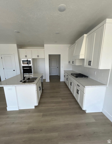 2818 West Aurora Avenue Mapleton, UT 84664 - Photo 2 of 9 Kitchen with white cabinets, light wood finished floors, light stone counters, an island with sink, and tasteful backsplash