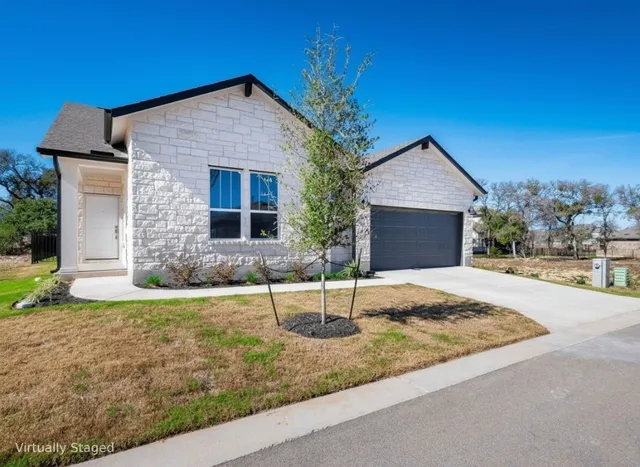 a front view of house with yard and trees in the background