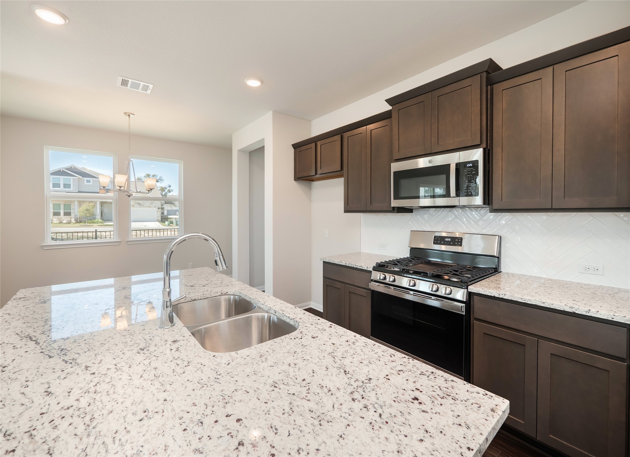 181 Soldier Street Kyle, TX 78640 - Photo 8 of 37 a kitchen with granite countertop a stove top oven microwave and refrigerator