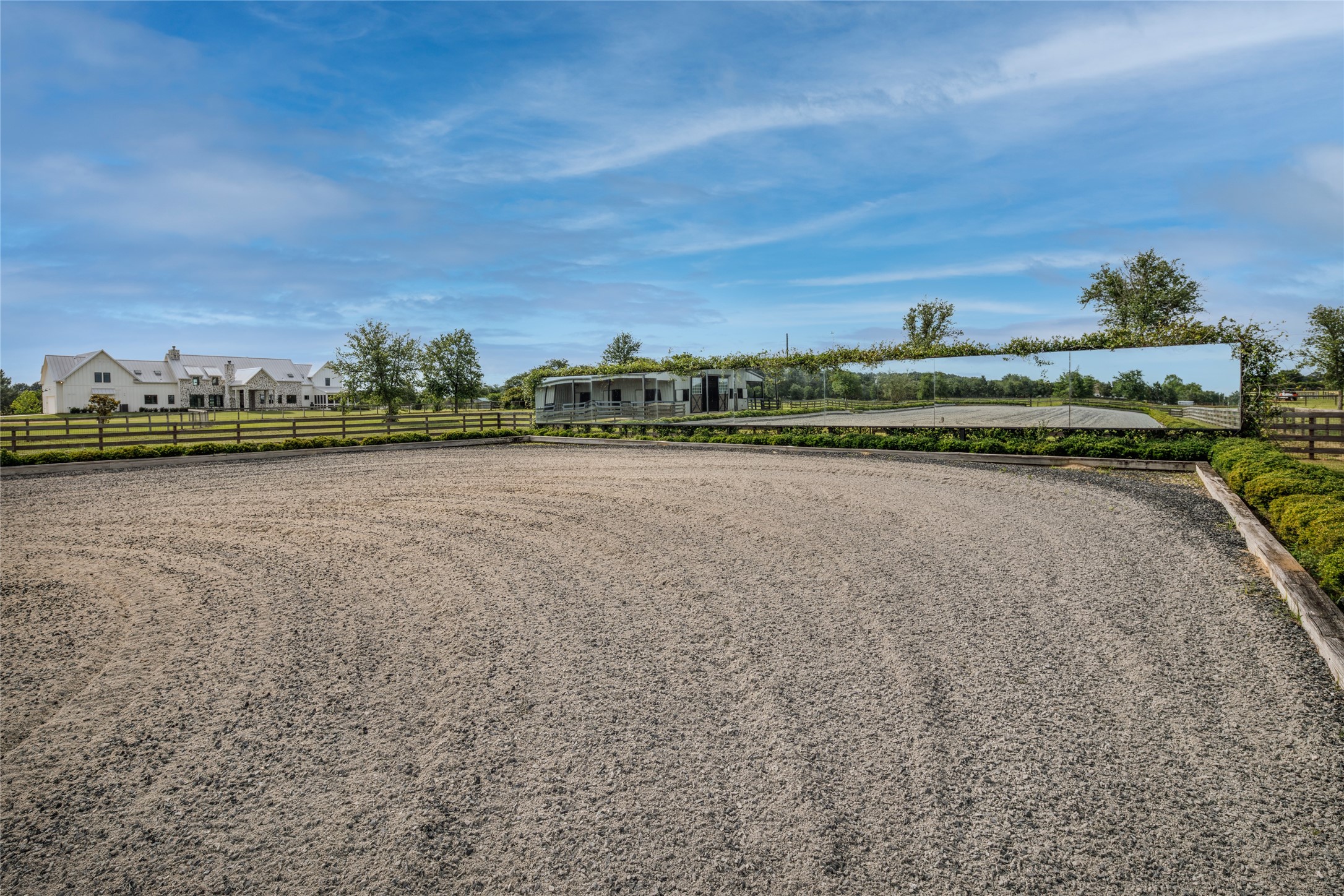24118 Margerstadt Road Hockley, TX 77447 - Photo 42 of 46 Professionally engineered footing, integrated irrigation, mirrored training walls, and expansive riding space create a setting designed for both training and everyday riding. Open pasture and surrounding paddocks keep the arena visually tied to the land around it.