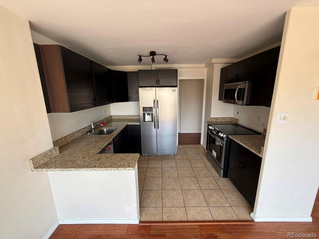 888 Logan Street, Unit 5H Denver, CO 80203 - Photo 5 of 25 a kitchen with stainless steel appliances granite countertop a sink stove and refrigerator