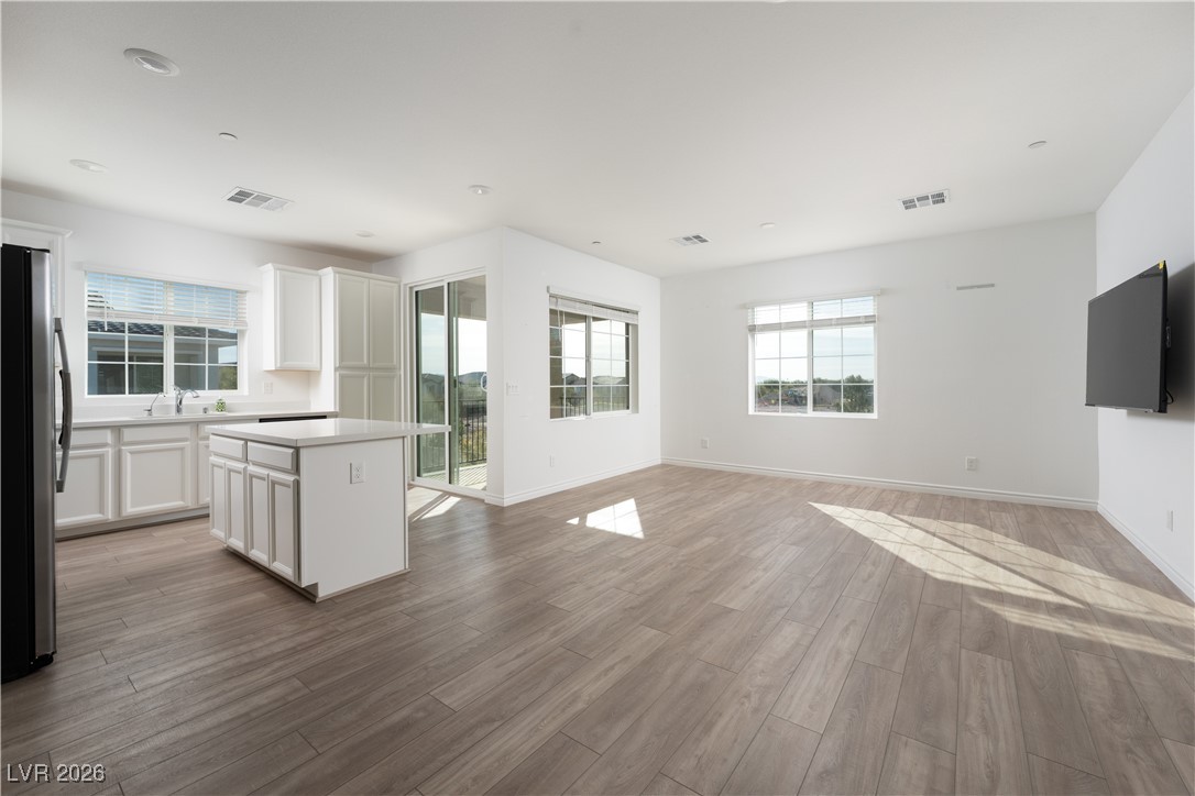 7330 North Decatur Boulevard, Unit 1 North Las Vegas, NV 89084 - Photo 29 of 29 Kitchen featuring white cabinetry, a center island, freestanding refrigerator, light wood-type flooring, and open floor plan