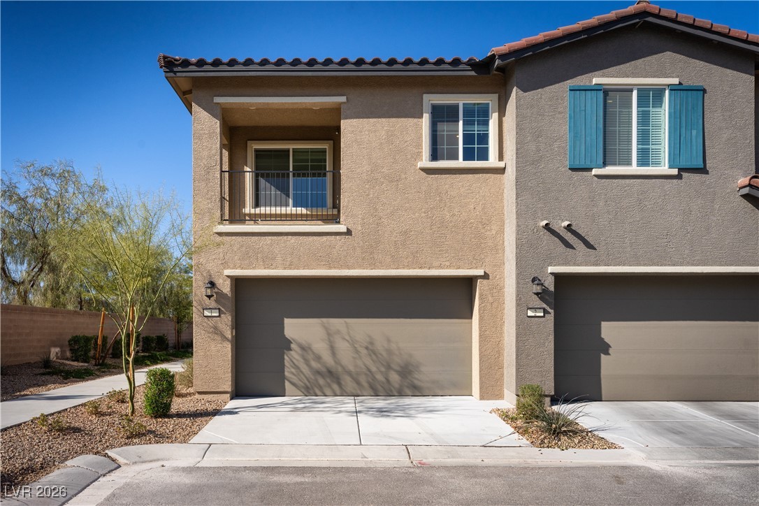 7330 North Decatur Boulevard, Unit 1 North Las Vegas, NV 89084 - Photo 4 of 29 Mediterranean / spanish house with a balcony, stucco siding, an attached garage, and driveway