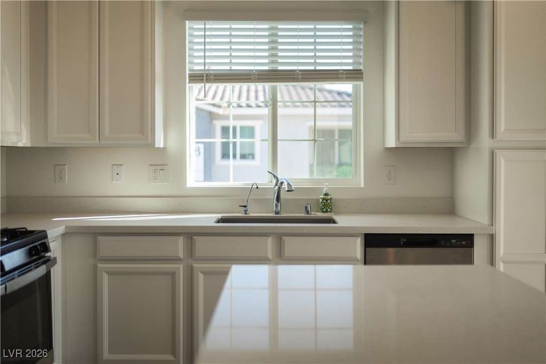 7330 North Decatur Boulevard, Unit 1 North Las Vegas, NV 89084 - Photo 7 of 29 Kitchen with stainless steel dishwasher, gas stove, white cabinetry, and light stone counters