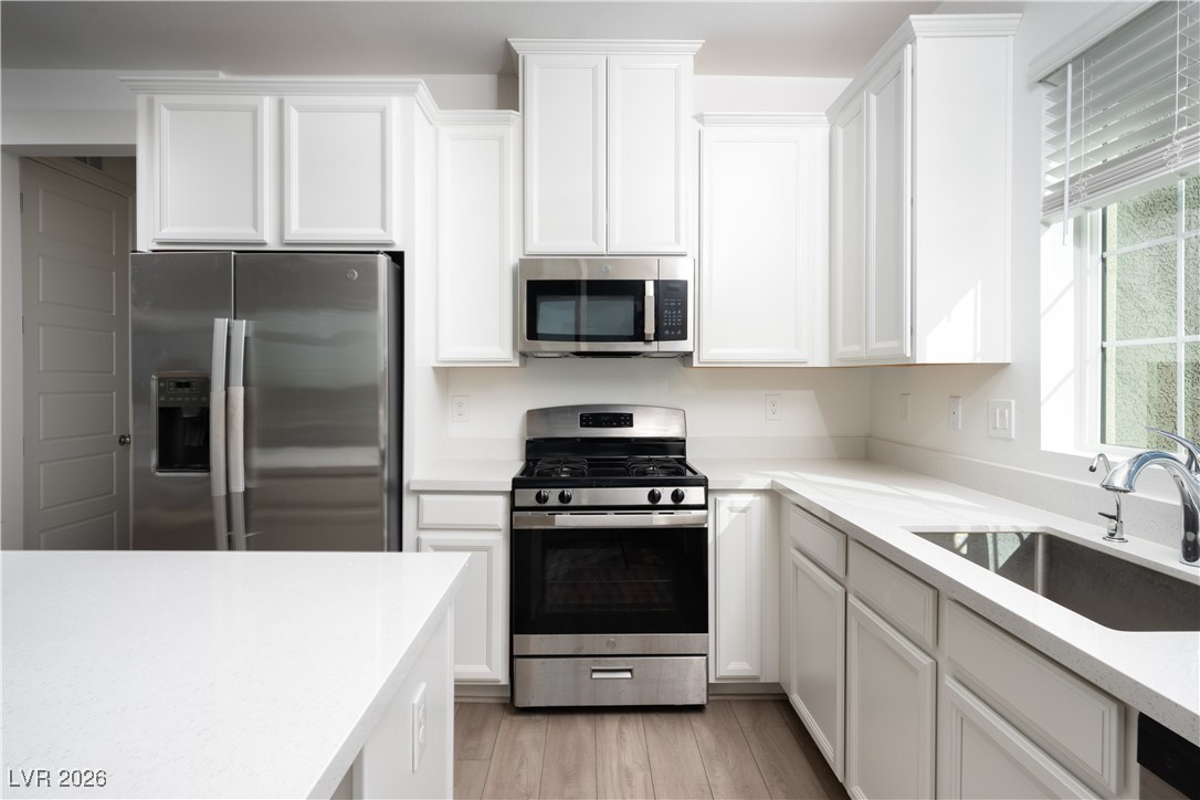 7330 North Decatur Boulevard, Unit 1 North Las Vegas, NV 89084 - Photo 8 of 29 Kitchen featuring stainless steel appliances, white cabinetry, light stone countertops, and light wood-style floors