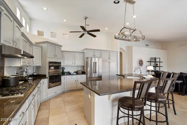 a kitchen with stainless steel appliances granite countertop a sink a stove a dining table and chairs