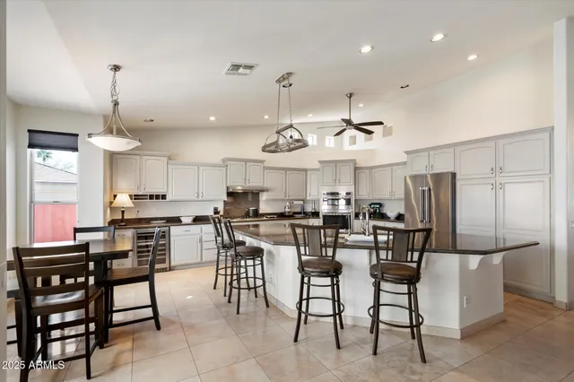 a kitchen with stainless steel appliances granite countertop a stove top oven a refrigerator a sink and chairs