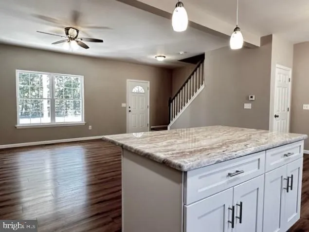 a kitchen with kitchen island a sink wooden floor and a ceiling fan