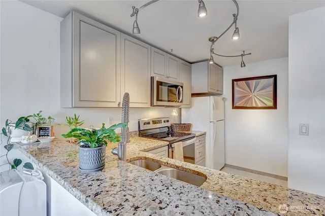 a kitchen with granite countertop a sink stainless steel appliances and cabinets