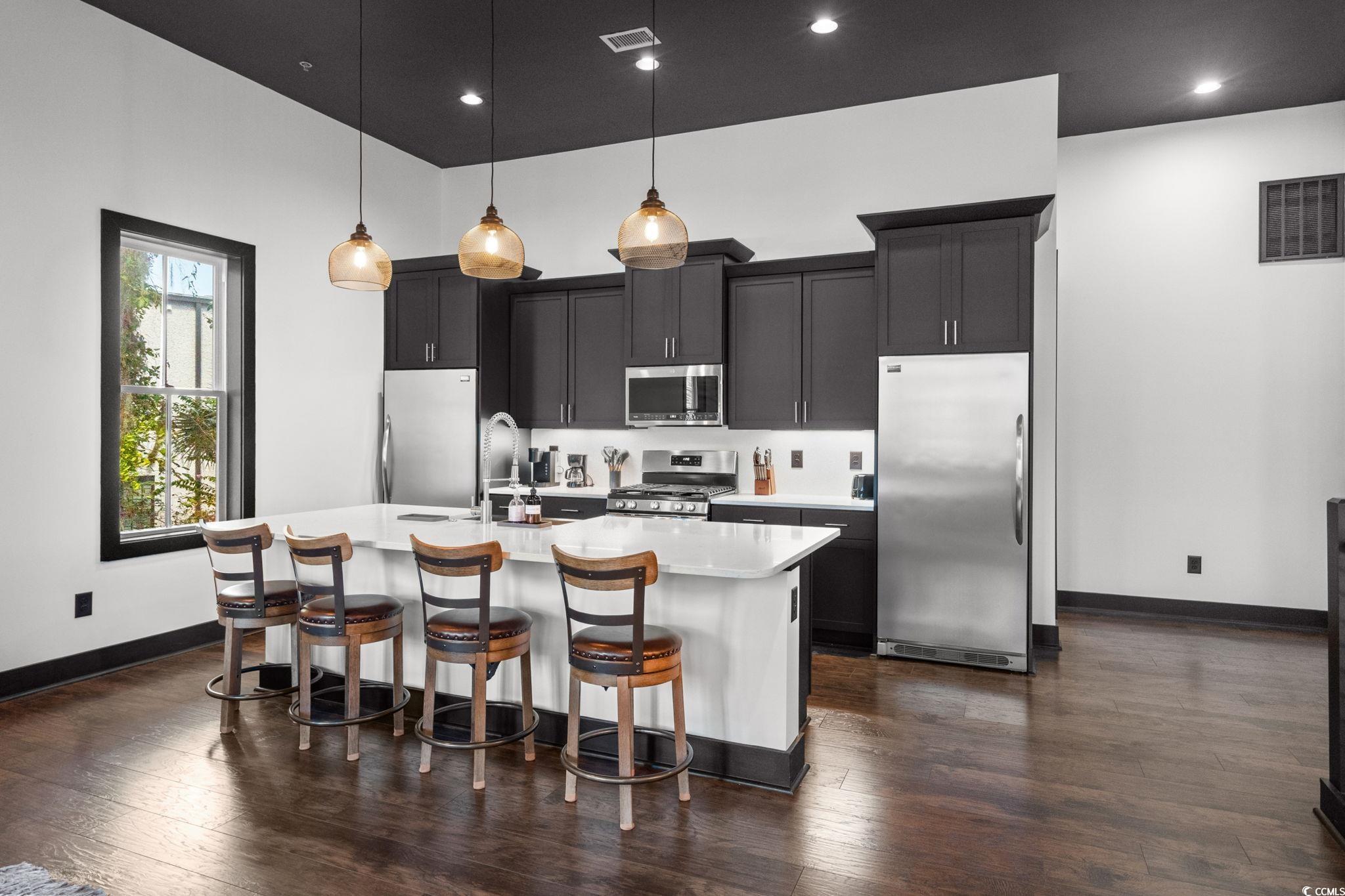 34 Shady Moss Loop, Unit 34 Murrells Inlet, SC 29576 - Photo 9 of 40 Kitchen with appliances with stainless steel finishes, a kitchen breakfast bar, hanging light fixtures, a kitchen island with sink, and dark wood finished floors