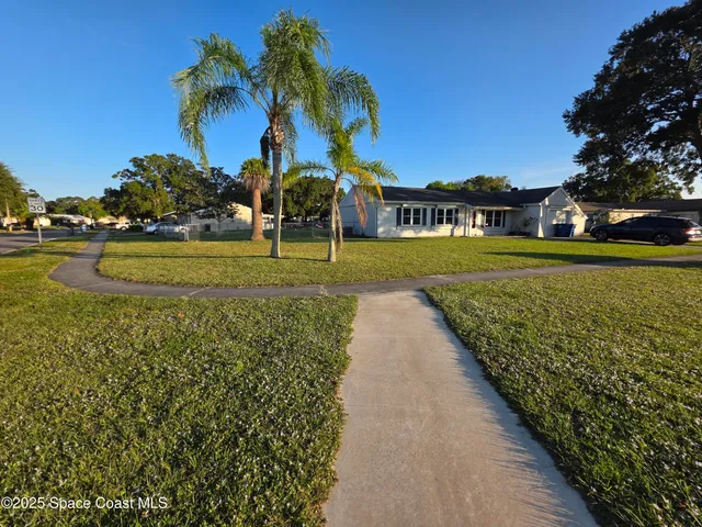 a view of a house with a big yard and palm trees