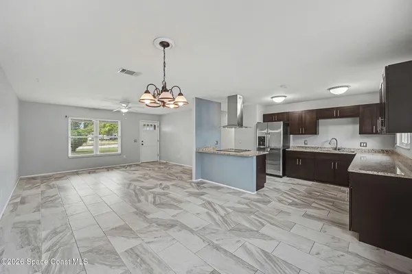 a large kitchen with granite countertop a sink refrigerator and cabinets