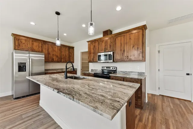 a kitchen with stainless steel appliances granite countertop a sink a stove and a wooden floors