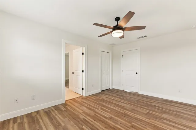 a view of empty room with wooden floor and ceiling fan