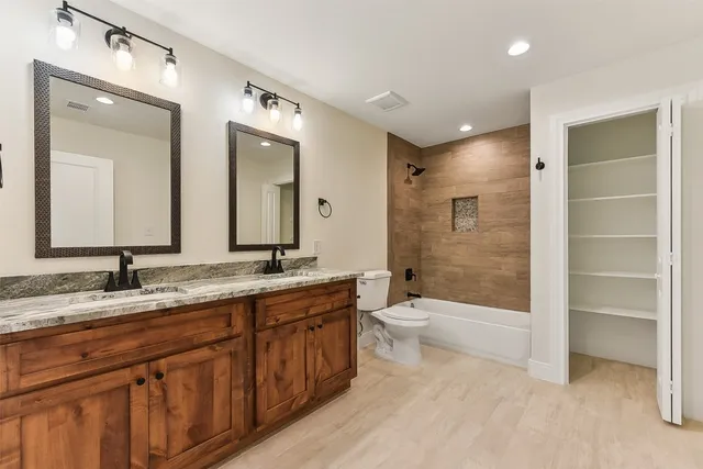 a bathroom with a granite countertop sink toilet mirror and bathtub
