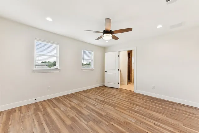 a view of empty room with wooden floor and fan