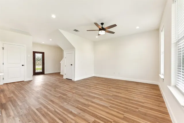 a view of an empty room with wooden floor and a window
