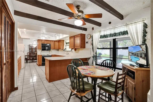 a dining room with stainless steel appliances kitchen island granite countertop a table chairs and a refrigerator