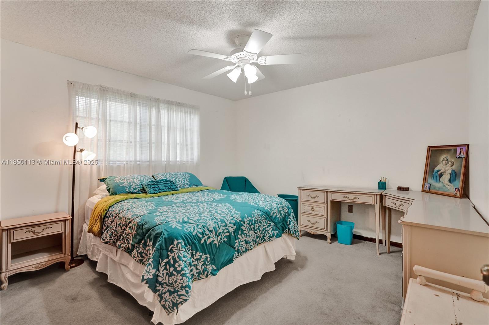 9461 Southwest 134th Street Miami, FL 33176 - Photo 25 of 33 a bed sitting in a bedroom next to a window with a chandelier