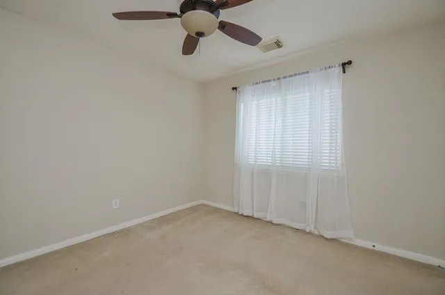 an empty room with a window and a fan