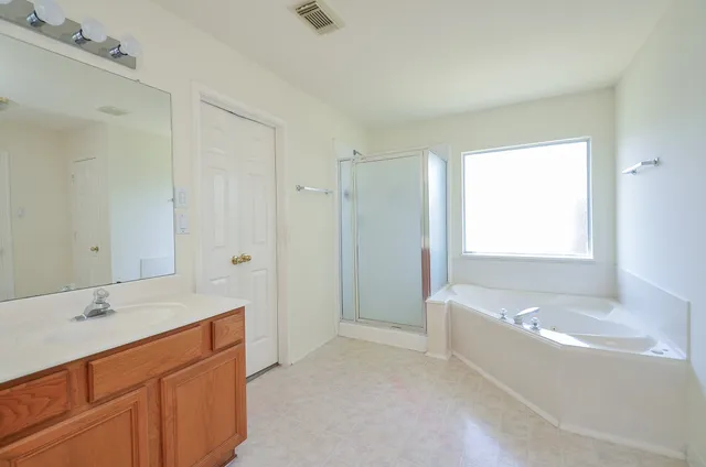 a bathroom with a tub sink shower and two mirror