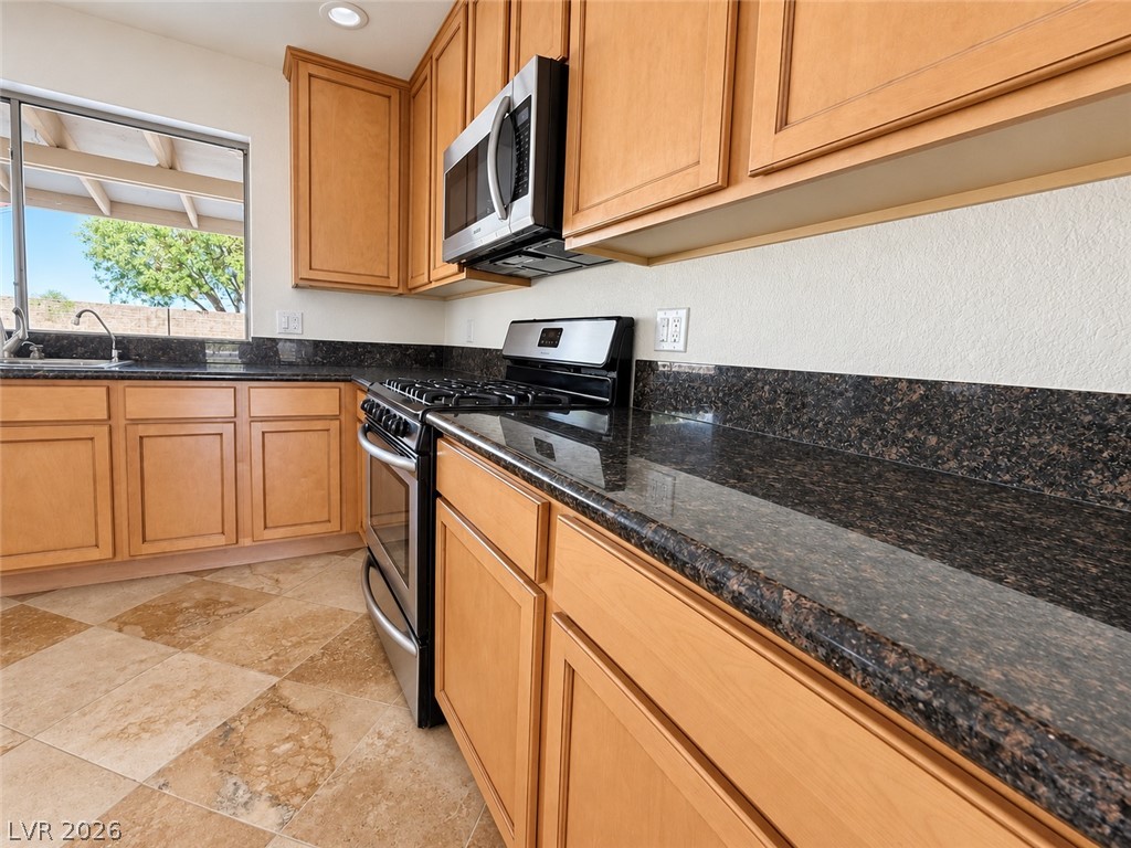 43 Bayridge Road Henderson, NV 89074 - Photo 26 of 47 Gleaming stone countertops and warm wood cabinetry highlight this functional culinary workspace.