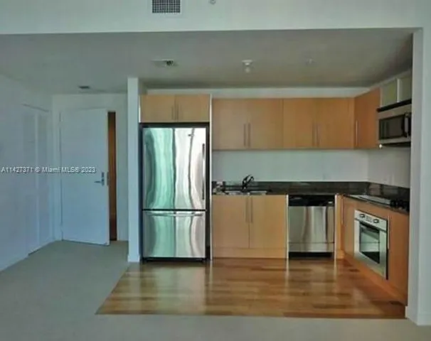 a kitchen with stainless steel appliances granite countertop a refrigerator and a stove top oven
