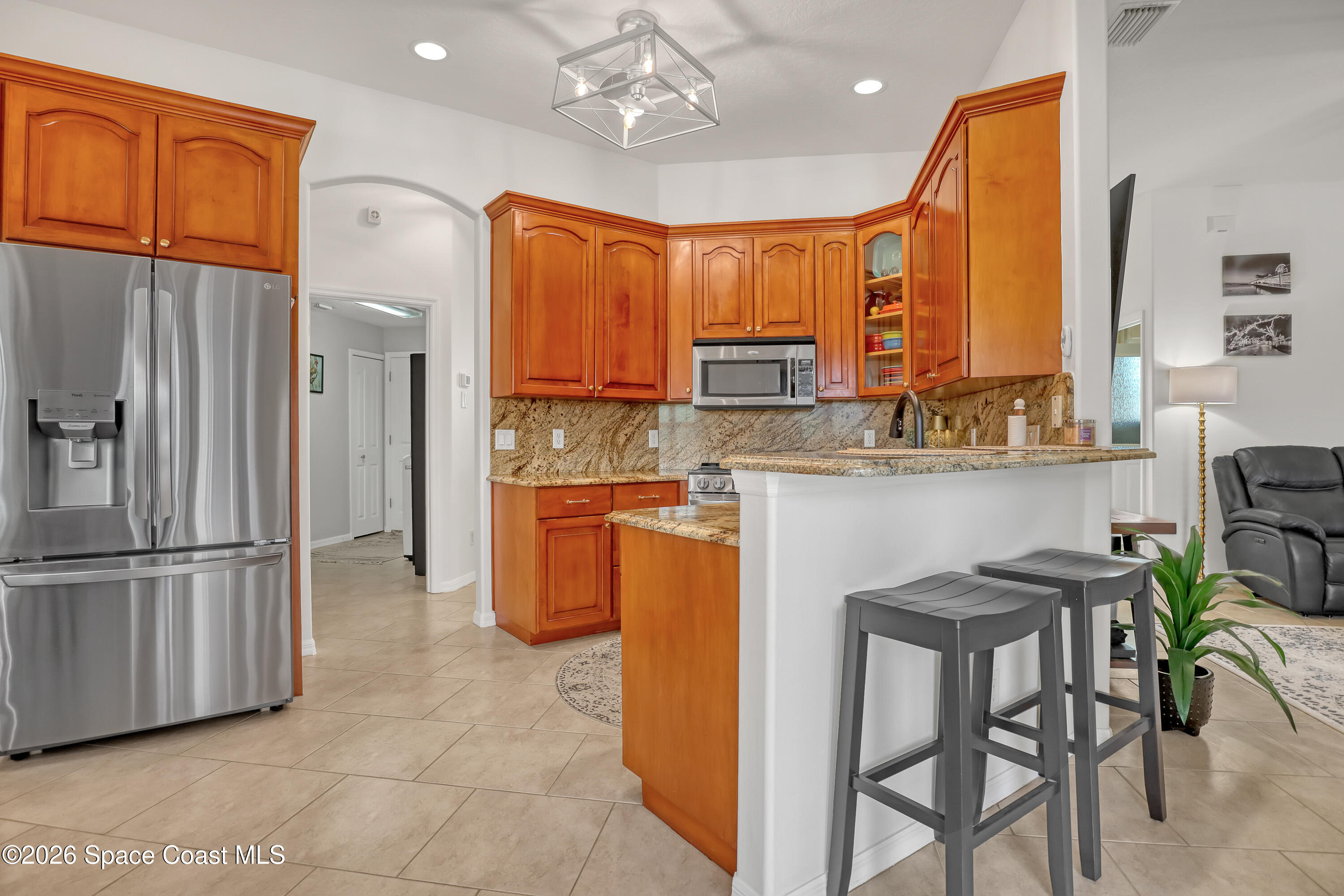 3120 Forest Creek Drive Melbourne, FL 32901 - Photo 20 of 59 a kitchen with stainless steel appliances granite countertop a refrigerator a stove a microwave oven a sink with island and chairs