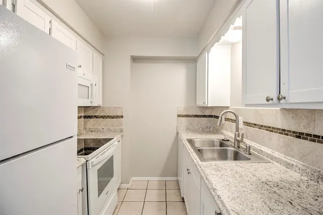 a kitchen with granite countertop a sink stove and refrigerator
