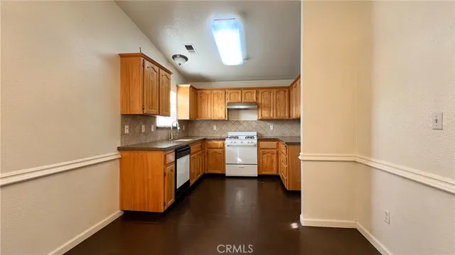 a kitchen with stainless steel appliances granite countertop a sink cabinets and wooden floor
