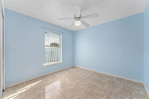 an empty room with windows and fan