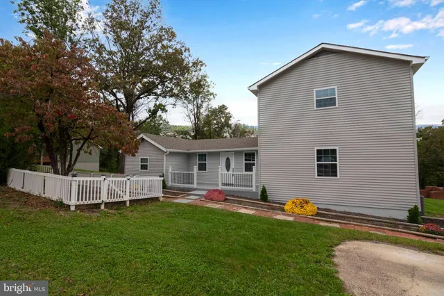 a view of a white house with a big yard and potted plants