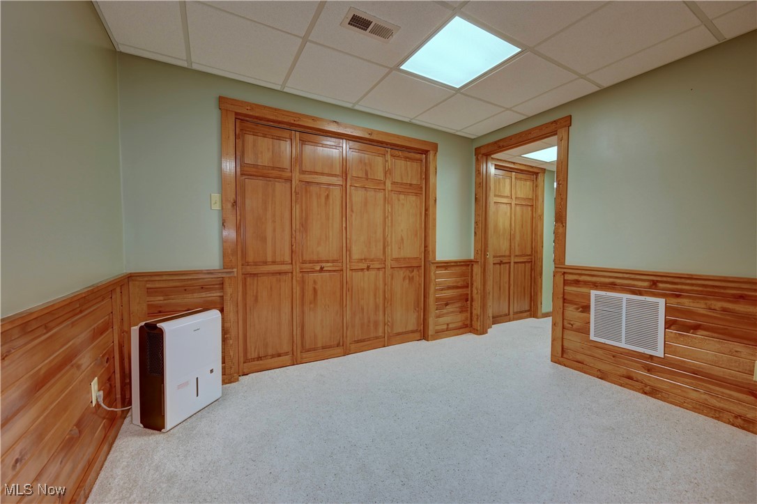 9559 Trail Bottom Road Northwest Dundee, OH 44624 - Photo 31 of 48 Unfurnished bedroom with wood walls, a wainscoted wall, a paneled ceiling, carpet, and a closet