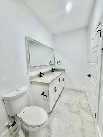a spacious bathroom with a granite countertop toilet sink and mirror
