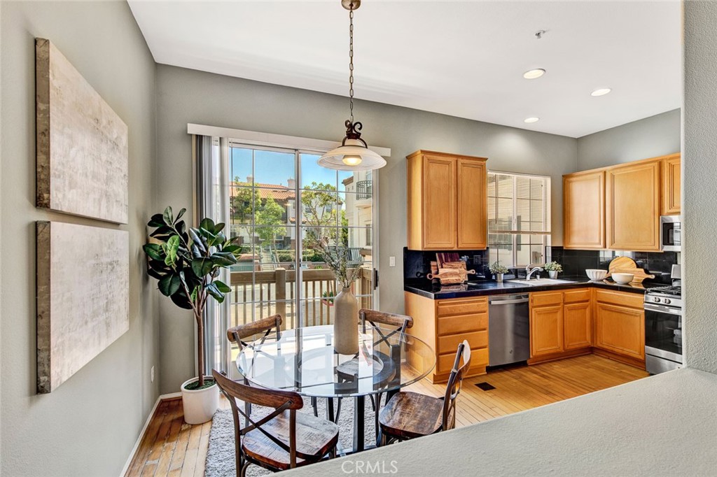 2830 Ballesteros Lane Tustin, CA 92782 - Photo 4 of 28 a kitchen with stainless steel appliances granite countertop a stove top oven a refrigerator a sink dishwasher a dining table and chairs with wooden floor