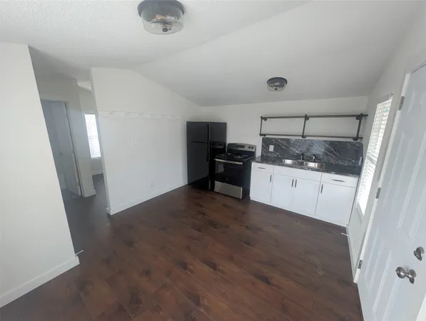 a kitchen with granite countertop a sink stove and refrigerator