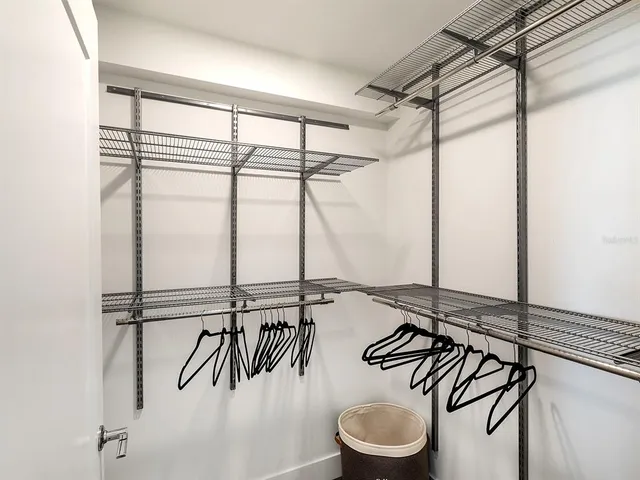 a view of a hallway with wooden floor and a bathroom