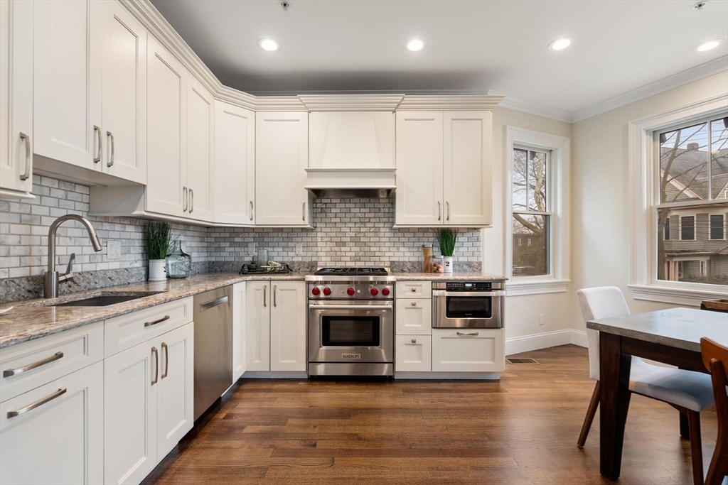 197 Rawson Road, Unit 1 Brookline, MA 02445 - Photo 4 of 27 a kitchen with granite countertop white cabinets and white appliances