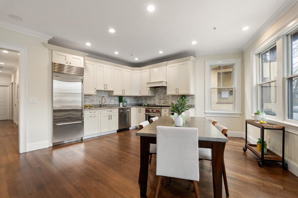 197 Rawson Road, Unit 1 Brookline, MA 02445 - Photo 5 of 27 a kitchen with a dining table chairs wooden floor appliances and cabinets