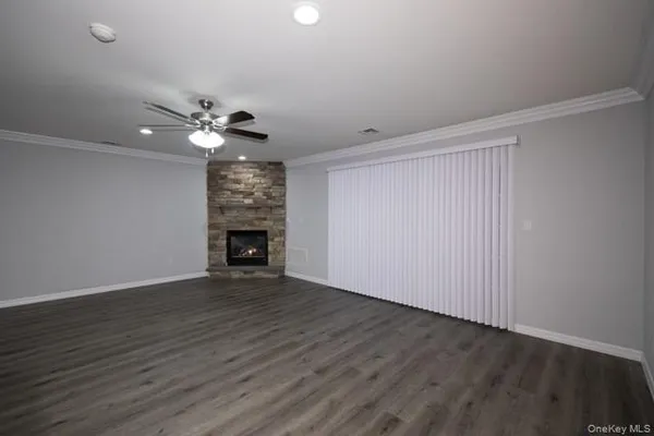a view of an empty room with wooden floor fireplace and a window
