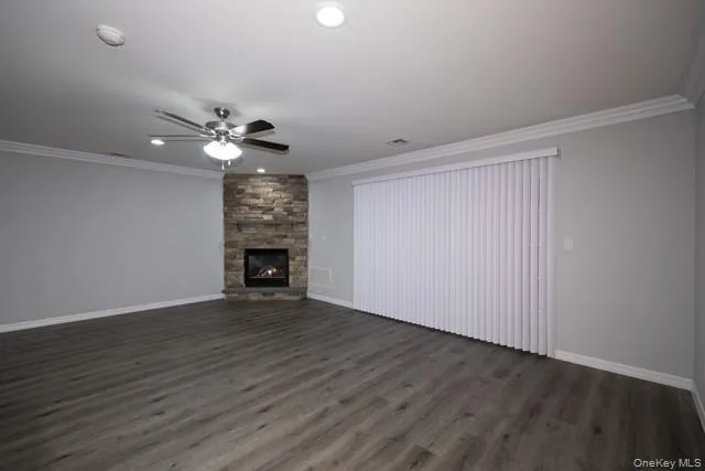 a view of an empty room with wooden floor fireplace and a window