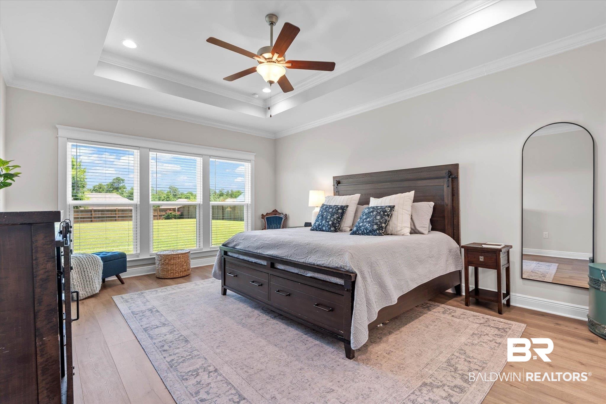 23523 Travis Stock Street Foley, AL 36535 - Photo 14 of 45 Spacious bedroom featuring wood-finish flooring, a tray ceiling with a ceiling fan, recessed lighting, and a triple window assembly overlooking the backyard