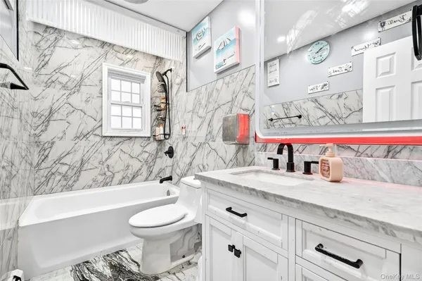 a bathroom with a granite countertop sink mirror vanity and toilet