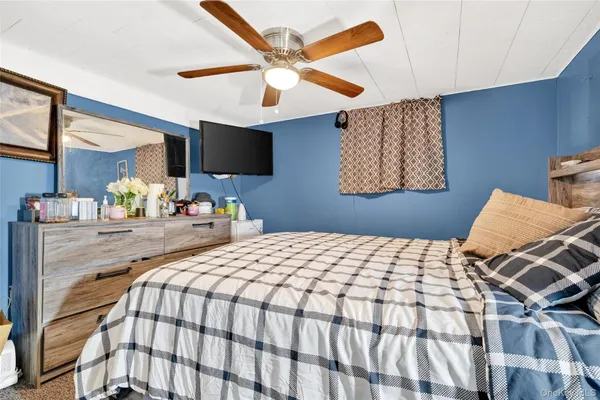 a bedroom with a bed and a flat tv screen on the dresser