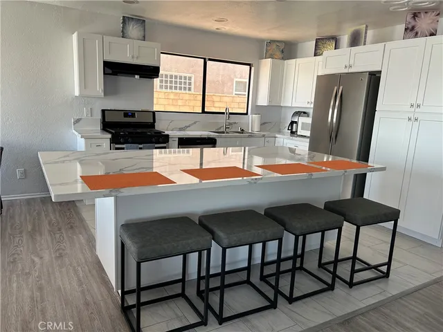 a kitchen with stainless steel appliances granite countertop a refrigerator a stove a sink dishwasher and a microwave oven with wooden floor